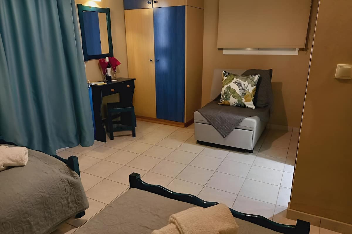 A hotel room with a bed, a desk, a chair, a sofa, and a wardrobe.