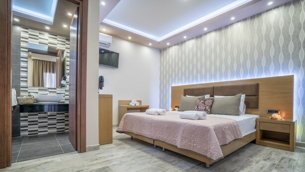 Une chambre moderne avec un grand lit, des tables de chevet, une coiffeuse avec un miroir et un téléviseur intégré.