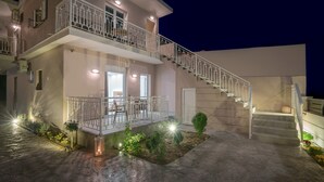 Un bâtiment à deux étages doté d’un balcon, d’un escalier et d’un petit jardin.