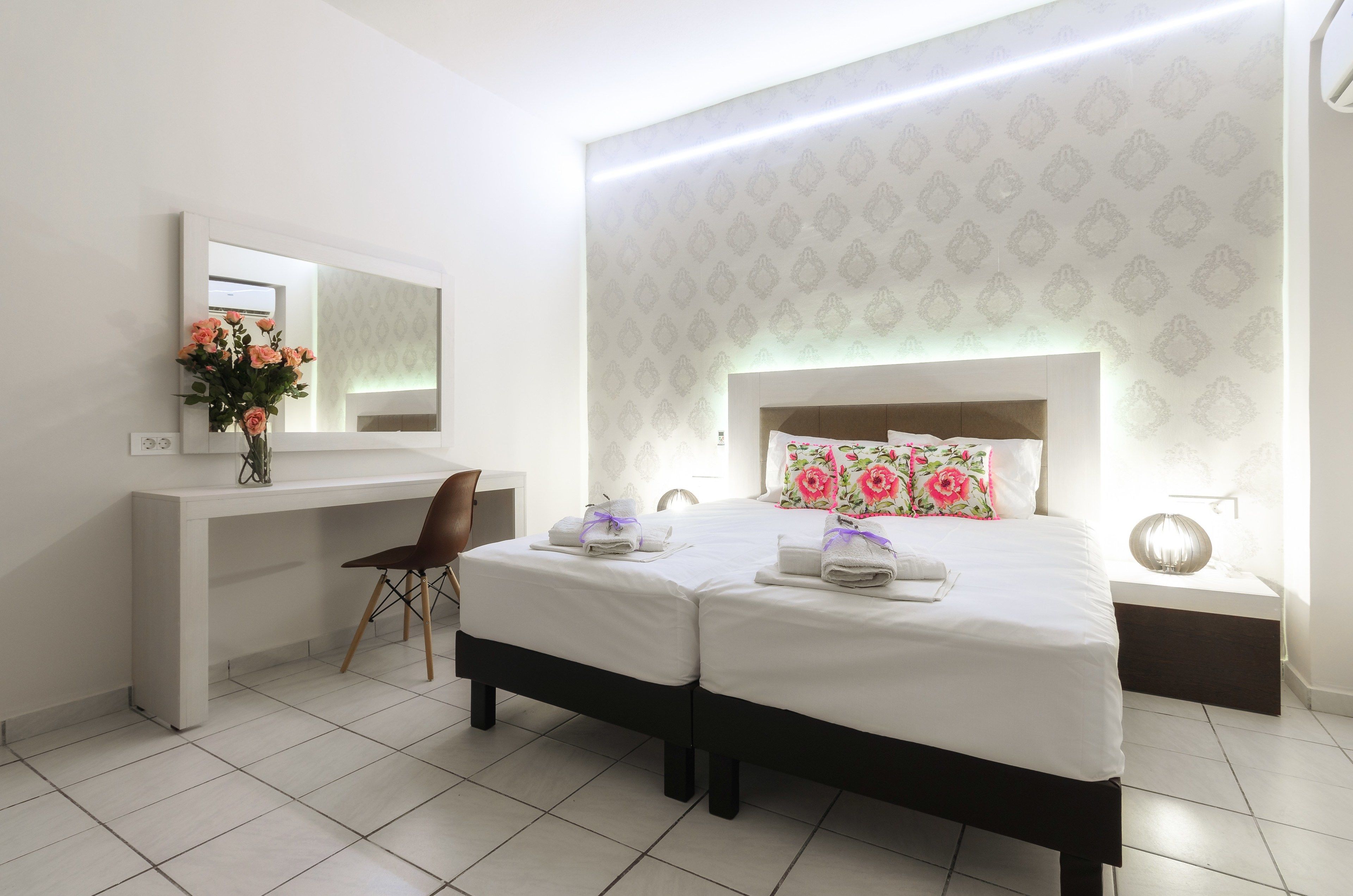 A modern hotel room with a large bed, a desk, and a chair.