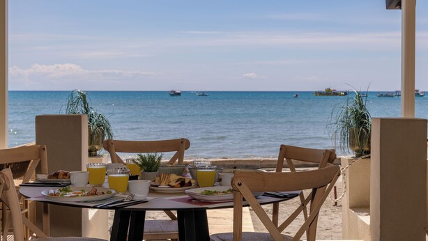 A table set for breakfast with a view of the sea and boats. - Mouria Studios & Apartments (Zakynthos)