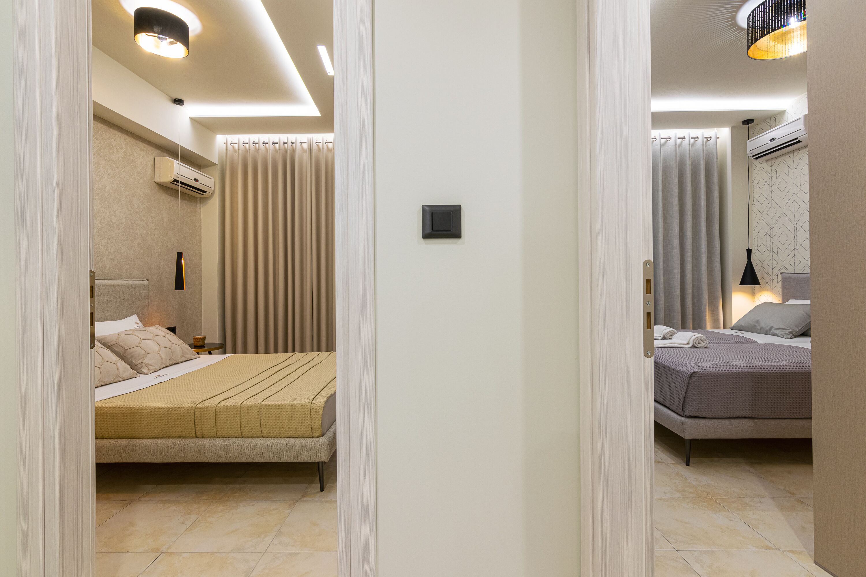 Une chambre d’hôtel avec deux lits, une petite table de chevet, un appareil de climatisation et un luminaire au plafond.