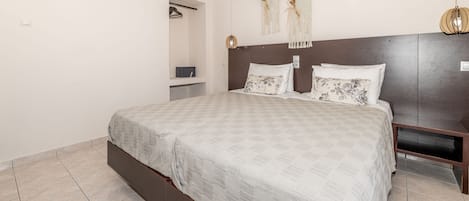 A bedroom with a large bed, a wooden headboard, a bedside table, a wardrobe, and a wall-mounted light fixture.