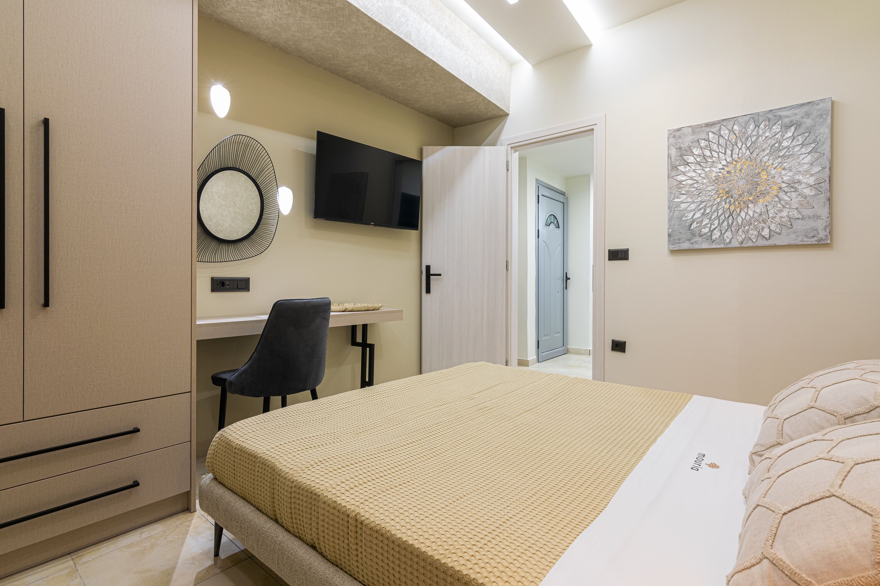 Una camera da letto con un letto, una scrivania, una sedia, una TV e una porta.