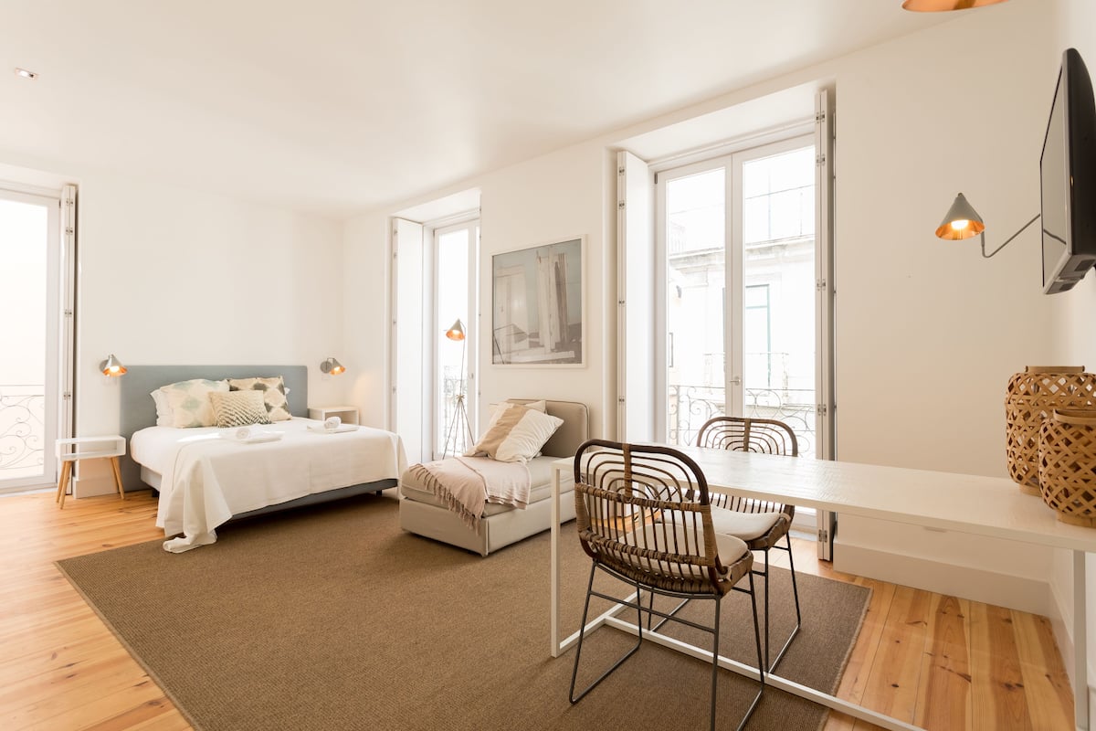 A modern bedroom with a bed, bedside tables, a desk, and a chair.