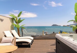 A balcony with a view of the sea, lounge chairs, a hot tub, and a wooden deck. - Pearl Luxury Living (Zakynthos)
