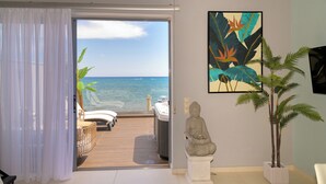 Quarto com vista para o oceano, uma estátua e uma pintura com tema tropical.