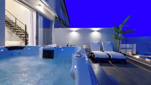 Uma área de piscina no terraço com hidromassagem, espreguiçadeiras e escadas que levam a um andar superior.