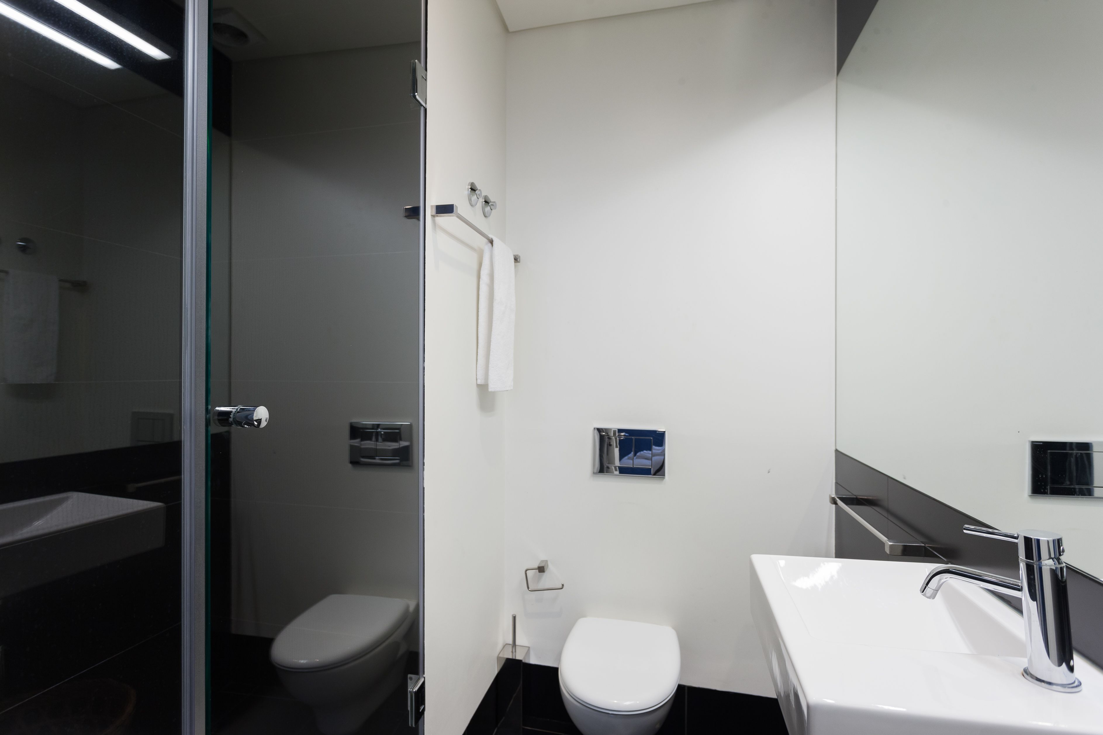 A modern bathroom with a toilet, sink, and glass shower enclosure.