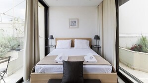 Quarto de hotel com uma cama grande, duas mesas de cabeceira, uma janela com cortinas e vista para o exterior.
