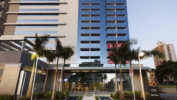 A modern hotel with a prominent "ibis budget" sign, a large glass entrance, and a clear view of the surrounding urban area.