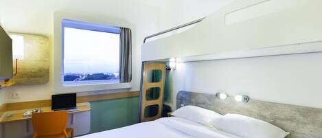 Habitación de hotel con cama, escritorio, silla y ventana con vistas.
