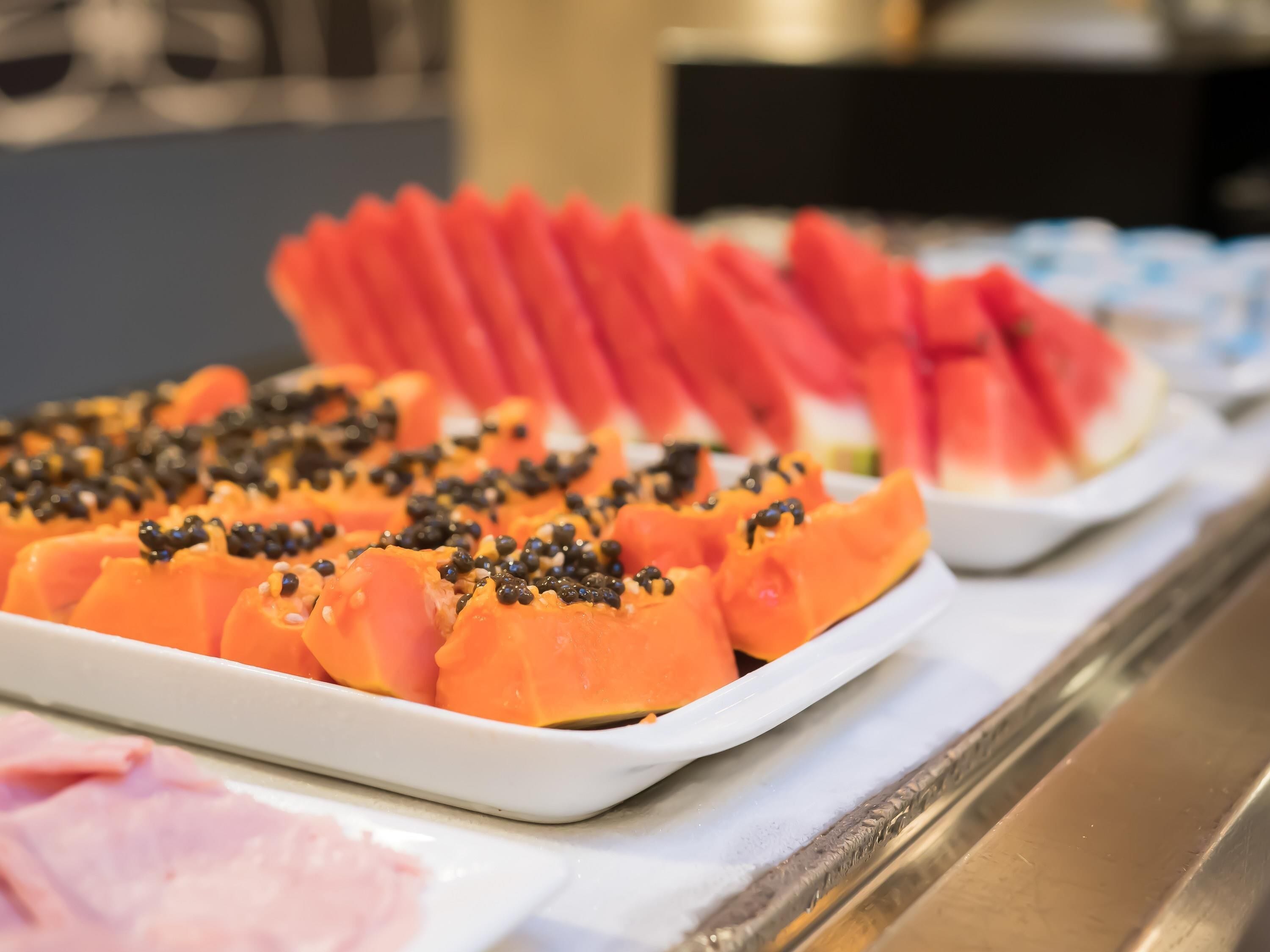 A buffet with sliced fruits and a white plate.