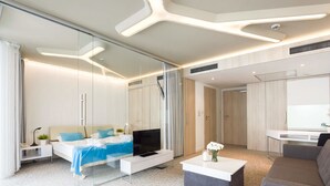 Una habitación de hotel moderna con cama, televisión, sofá y escritorio.