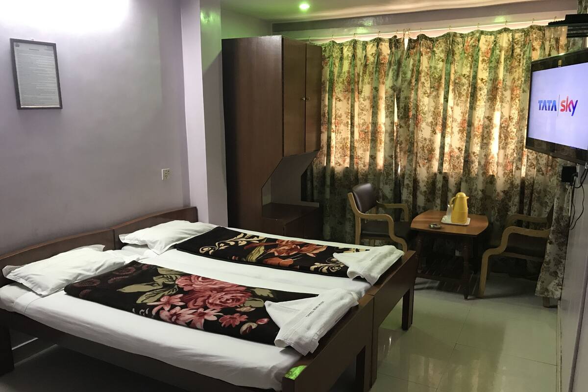 A hotel room with a bed, a desk, a chair, a television, and a wardrobe.