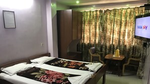 Una habitación de hotel con una cama, un escritorio, una silla, un televisor y un armario.