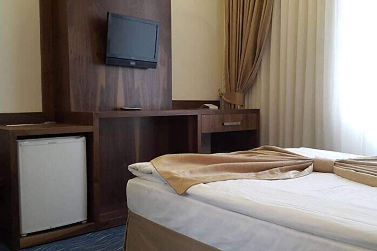 Una habitación de hotel con una cama, un escritorio, televisión y minibar.