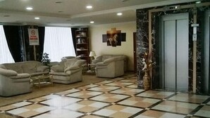 A lobby with a checkered floor, sofas, a bookshelf, and a marble column. - Miroglu Hotel (Diyarbakir)