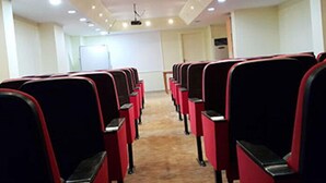 A conference room with rows of red and black chairs, a whiteboard, and a projector on the ceiling. - Miroglu Hotel (Diyarbakir)