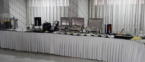 A buffet setup with a white tablecloth, multiple serving stations, and a patterned floor design.