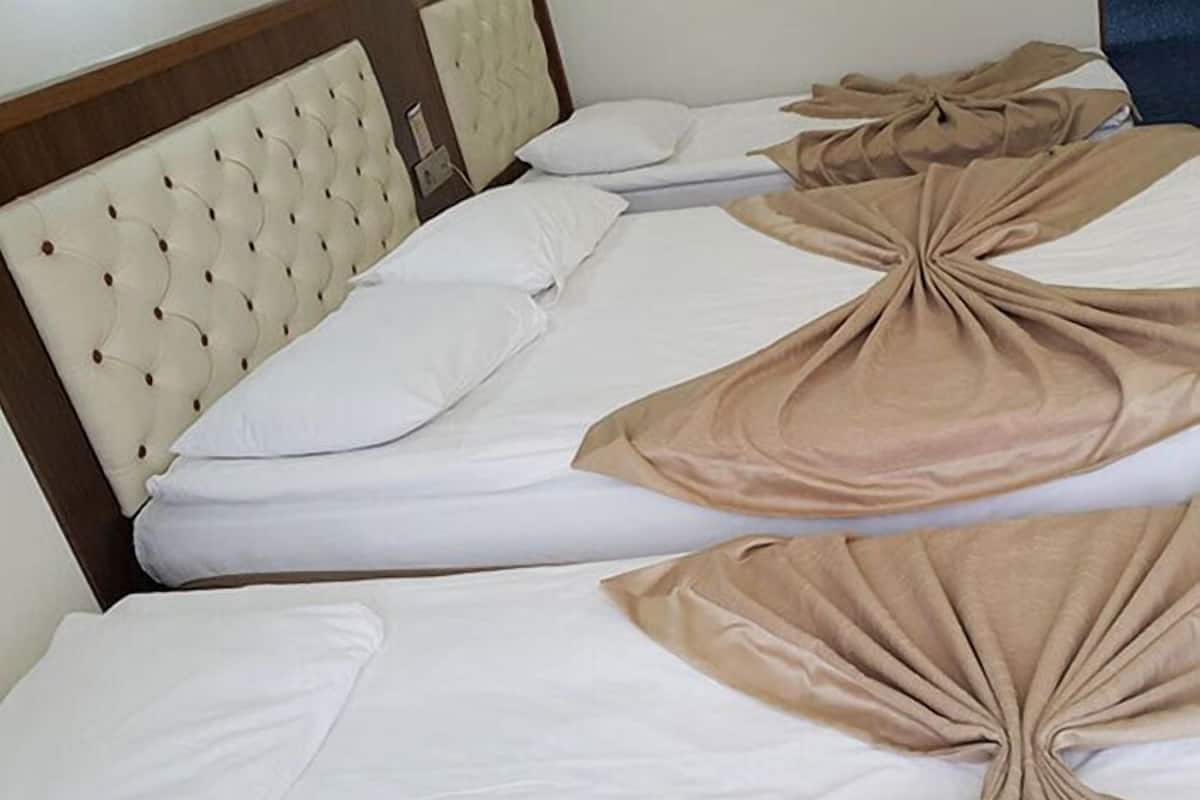 Habitación de hotel con dos camas, cada una con cabecera y ropa de cama blanca.