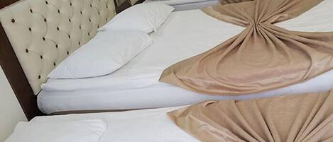 Habitación de hotel con dos camas, cada una con cabecera y ropa de cama blanca.