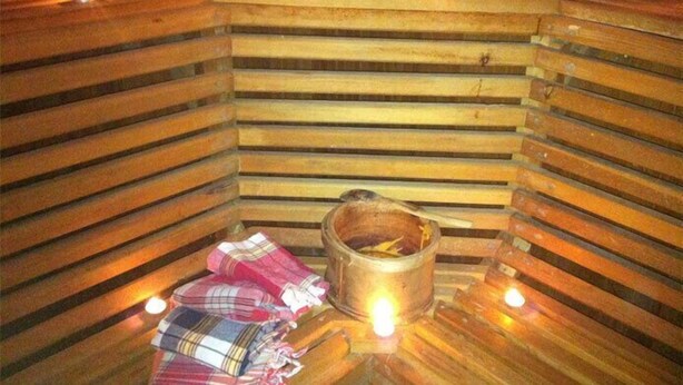 A sauna with wooden benches, a bucket, and candles. - Miroglu Hotel (Diyarbakir)