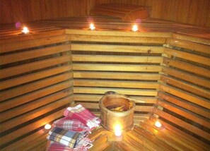 A sauna with wooden benches, a bucket, and candles. - Miroglu Hotel (Diyarbakir)
