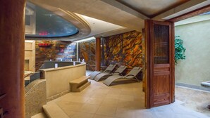 A spa area with a reception desk, seating area, and a stone wall. - VacationClub - Nadbrzeżna Apartments (Mielno)