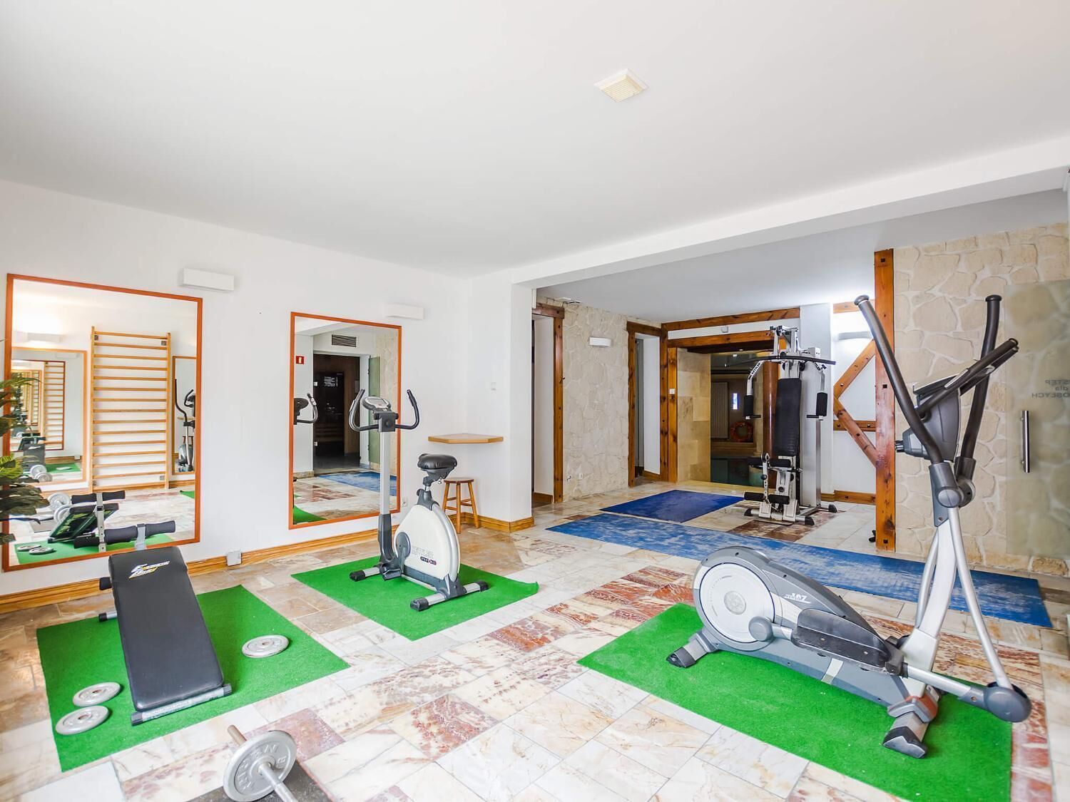 Un gimnasio con equipo de ejercicio, una banca y un espejo.