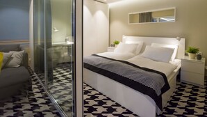 A modern bedroom with a large bed, a glass partition, and a patterned floor. - VacationClub - Nadbrzeżna Apartments (Mielno)