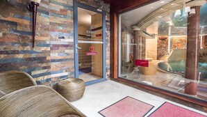 A hotel entrance with a stone wall, a glass door, wicker furniture, and a red mat. - VacationClub - Nadbrzeżna Apartments (Mielno)