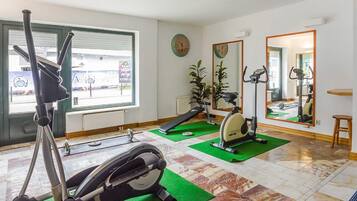 Un gimnasio con equipo de ejercicio, un ventanal y un espejo.