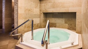 A spa area with a hot tub, marble walls, and a tiled floor. - VacationClub - Nadbrzeżna Apartments (Mielno)