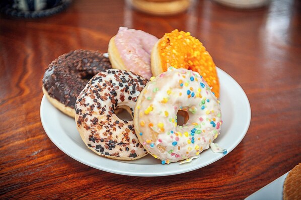 Un plato con cuatro donas diferentes sobre una mesa de madera.