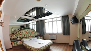 Ein Hotelzimmer mit einem großen Bett, einem Fernseher, einem Schreibtisch und einem Sessel.