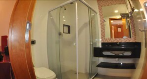 Un baño con ducha de vidrio, inodoro y lavamanos con encimera negra.