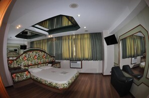 Un dormitorio con cama, espejo, televisión y ventilador de techo.