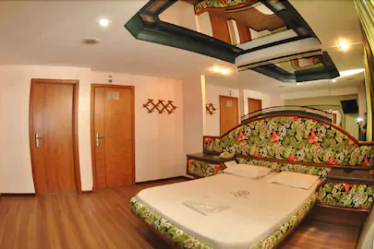 Un dormitorio con una cama, dos puertas, un espejo y un techo con diseño geométrico.