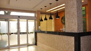 Ein Empfangsbereich mit Glastür, Empfangstresen und Pendelleuchten.