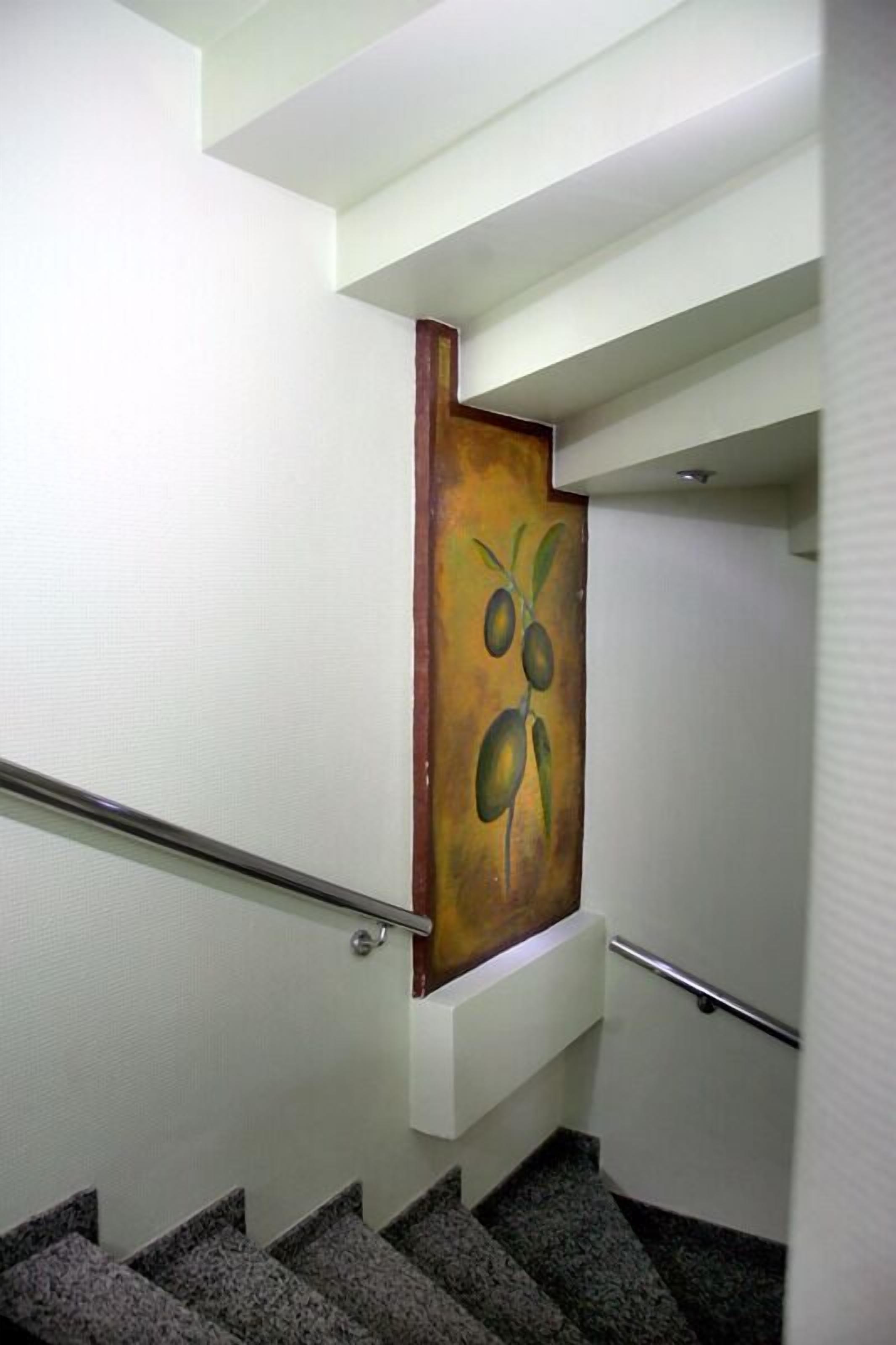 A staircase with a handrail and a painting of olives on the wall.