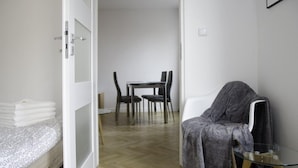 A small, modern room with a bed, a table with chairs, and a glass table with a chair. - Bizzi LuxHeart of Old Town Apartment (Warsaw)