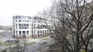 A multi-story building with a curved facade, surrounded by bare trees and a road with parked cars. - Bizzi LuxHeart of Old Town Apartment (Warsaw)