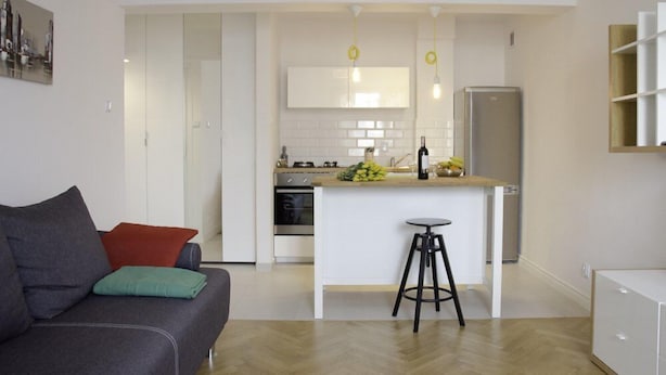A modern kitchen with white cabinetry, a central island, and a bar stool. - Bizzi LuxHeart of Old Town Apartment (Warsaw)
