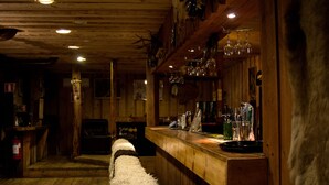 Un coin bar rustique avec des murs en bois, un banc recouvert de fourrure et divers outils et bouteilles de bar.