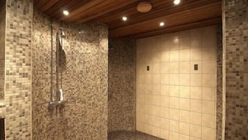 A shower area with mosaic tile walls and a wooden ceiling.