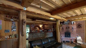 Un intérieur rustique avec des poutres apparentes, une cheminée en pierre et un canapé en cuir.