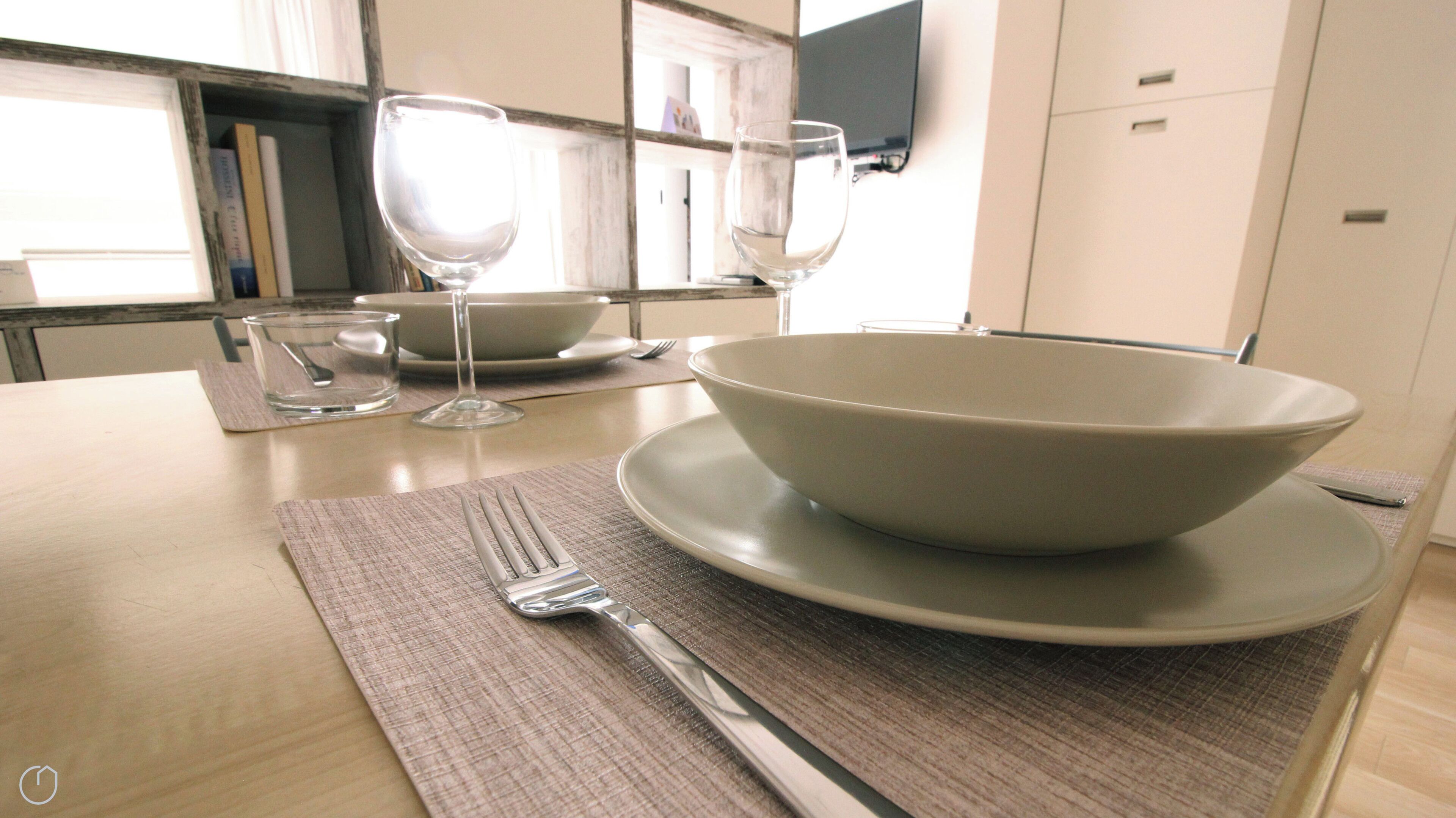 Une table à manger avec un bol, une assiette, une fourchette et un verre à vin.