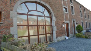 A brick building with a large arched window and a door. - Sommette (Somme-Leuze)