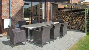 An outdoor patio with a table and chairs, a large umbrella, and a brick wall. - Sommette (Somme-Leuze)
